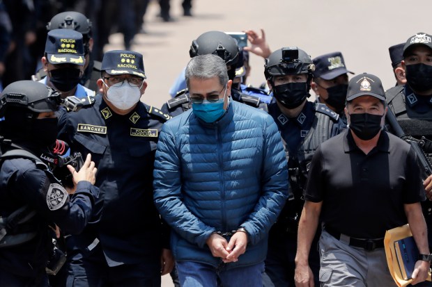 Former President of Honduras Juan Orlando Hernandez is escorted by Members of the Police Special Forces to be extradited to U.S.to face charges of taking bribes from drug traffickers at Honduran National Directorate of Special Forces on April 21, 2022 in Tegucigalpa, Honduras. Hernandez will stand trial for allegedly aiding the smuggling of hundreds of tons of cocaine to America (Photo by Jorge Cabrera/Getty Images)